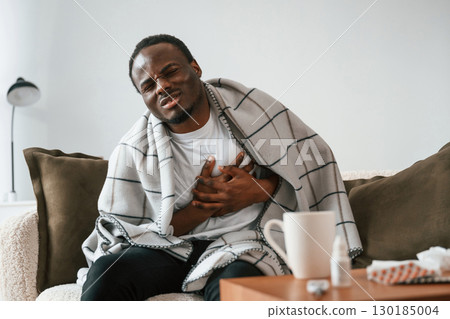 Pain in the heart area. Sick black man is at home Pain in the heart area. Sick black man is at home 130185004