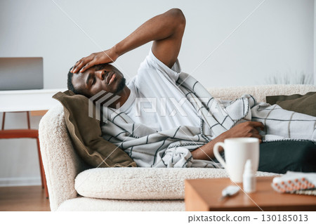 Lying down on the sofa. Sick black man is at home Lying down on the sofa. Sick black man is at home 130185013