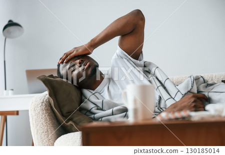 Lying down on the sofa. Sick black man is at home 130185014