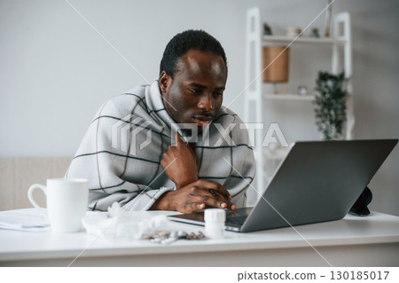 Working from home by laptop. Feeling bad. Sick black man is at home 130185017