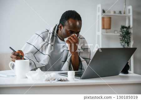 Working from home by laptop. Feeling bad. Sick black man is at home 130185019