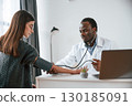 Customer service. A doctor measures a young woman's blood pressure 130185091