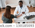 Customer service. A doctor measures a young woman's blood pressure 130185093