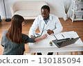 Customer service. A doctor measures a young woman's blood pressure 130185094