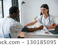 Sitting by a table. Female doctor measures blood pressure of a man 130185095