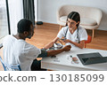 Female doctor measures blood pressure of a man 130185099