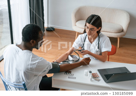 Female doctor measures blood pressure of a man Female doctor measures blood pressure of a man 130185099