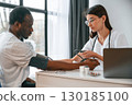 Female doctor measures blood pressure of a man 130185100