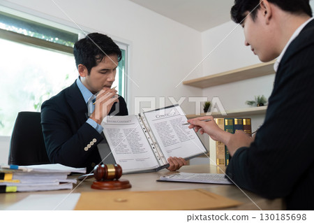 Legal Consultation. Two lawyers reviewing a contract in an office setting. 130185698