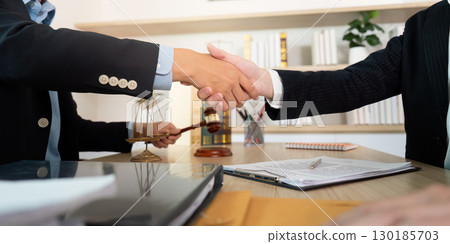 Legal Agreement. Lawyers shaking hands with a gavel and scales in view. Legal Agreement. Lawyers shaking hands with a gavel and scales in view. 130185703