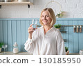 Healthy Lifestyle A Woman Delightfully Enjoying a Refreshing Beverage in a Modern and Stylish Kitchen Space 130185950