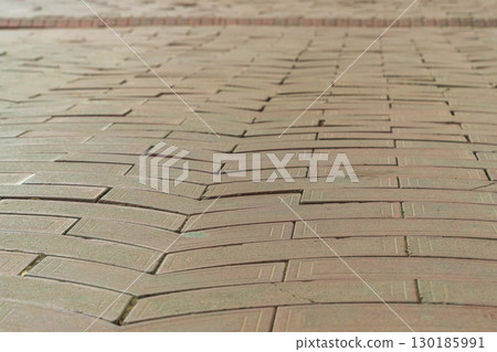 Surface of paved pedestrian sidewalk close-up with perspective stretching into distance with guiding lines of contour shapes of tiles pointing to right direction of movement, hint from above, an omen 130185991