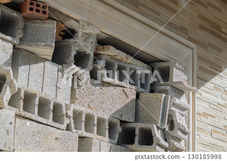 The window opening of an unfinished house is temporarily closed by superimposed building blocks during construction process until the installation of the window frame. Preparation for installation 130185998