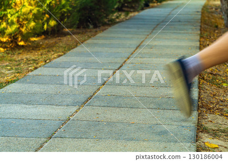 Pedestrian walking path with perspective stretching into distance, One leg of running white man washed out due to movement as he strays from straight path into unknown territory outside road 130186004