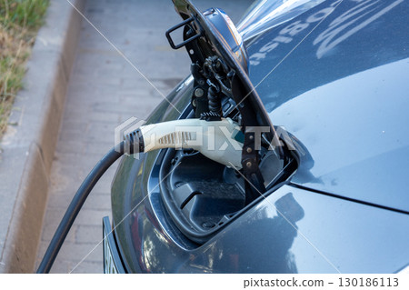 A modern electric vehicle is connected to a charging station, showcasing the importance of sustainable transportation methods A modern electric vehicle is connected to a charging station, showcasing the importance of sustainable transportation methods 130186113