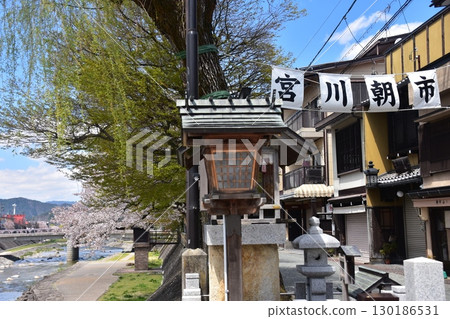 Takayama City, Gifu Prefecture, Japan - Miyagawa River flowing through the center of the city and the tourist attraction Miyagawa Morning Market - Cherry blossoms in full bloom and a beautiful blue sky - mid-afternoon 130186531
