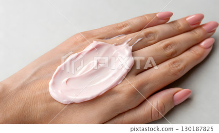 Hand with pink cream applied on it during skincare routine at home 130187825
