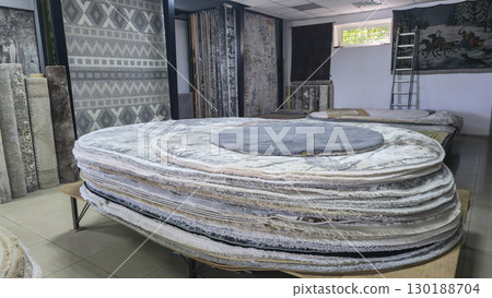Carpets and rugs lie on the counters and hang on the stands for sale Carpet shop 130188704