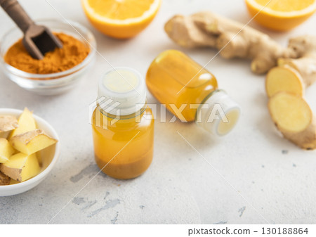 Turmeric energy shot immune drink with ginger root and ripe oranges on light background.Macro. 130188864
