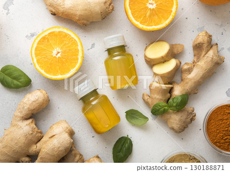 Immune turmeric energy shot drink with fresh raw ginger root and oranges on light background. Immune turmeric energy shot drink with fresh raw ginger root and oranges on light background. 130188871