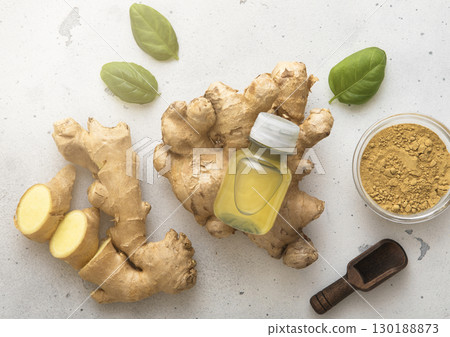 Bottle of immune ginger energy shot drink with ginger root and grounded powder on light background. Bottle of immune ginger energy shot drink with ginger root and grounded powder on light background. 130188873