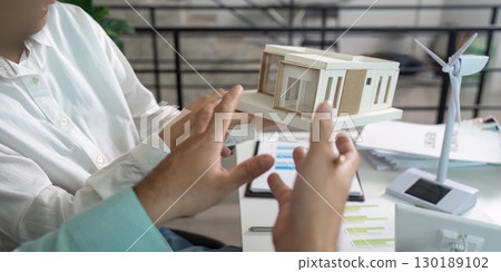 Sustainability in Architecture. Professionals discussing eco-friendly building models and renewable energy solutions. Sustainability in Architecture. Professionals discussing eco-friendly building models and renewable energy solutions. 130189102