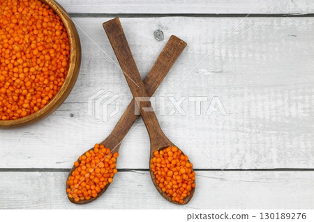 Red lentils in wooden bowl on wooden table background. Top view, copy space. Flat lay. 130189276