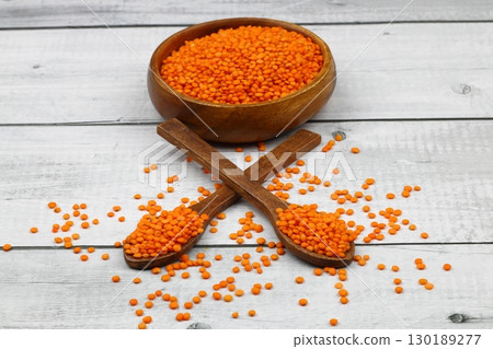 Red lentils in wooden bowl on wooden table background. Top view, copy space. Flat lay. 130189277