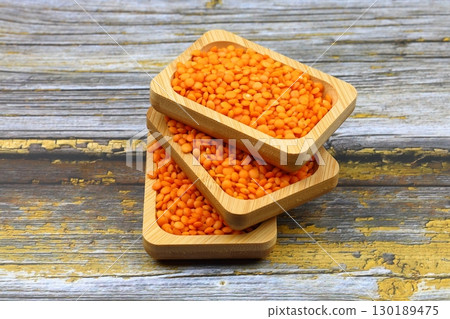 Red lentils in wooden bowl on wooden table background. Top view, copy space. Flat lay. Red lentils in wooden bowl on wooden table background. Top view, copy space. Flat lay. 130189475