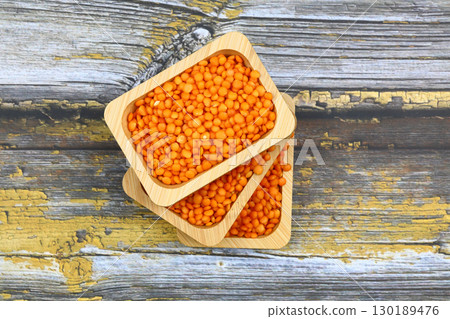 Red lentils in wooden bowl on wooden table background. Top view, copy space. Flat lay. Red lentils in wooden bowl on wooden table background. Top view, copy space. Flat lay. 130189476