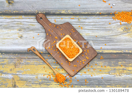 Red lentils in wooden bowl on wooden table background. Top view, copy space. Flat lay. 130189478