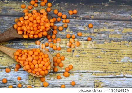Red lentils in wooden bowl on wooden table background. Top view, copy space. Flat lay. 130189479