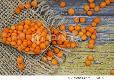 Red lentils in wooden bowl on wooden table background. Top view, copy space. Flat lay. 130189480