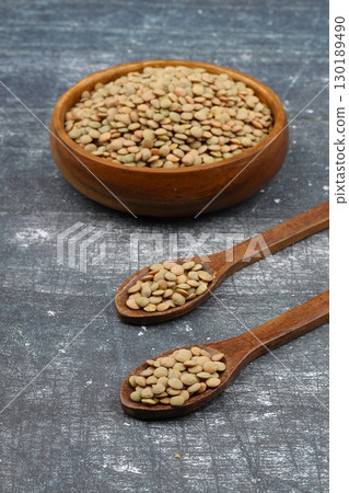 Green lentils in wooden bowl on wooden table background. Top view, copy space. Flat lay. Green lentils in wooden bowl on wooden table background. Top view, copy space. Flat lay. 130189490