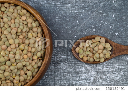 Green lentils in wooden bowl on wooden table background. Top view, copy space. Flat lay. Green lentils in wooden bowl on wooden table background. Top view, copy space. Flat lay. 130189491