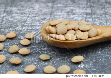Pile lentil in wooden spoon isolated on wooden background. Top view. Pile lentil in wooden spoon isolated on wooden background. Top view. 130189492