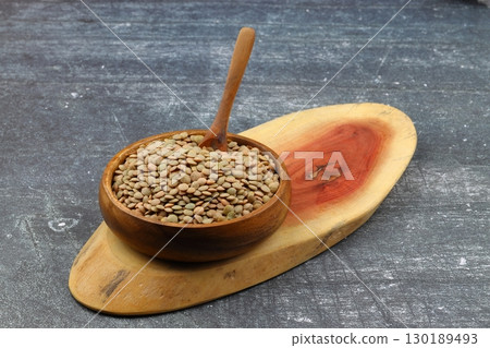 Green lentils in wooden bowl on wooden table background. Top view, copy space. Flat lay. 130189493