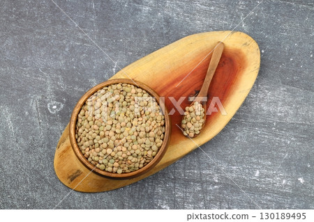 Green lentils in wooden bowl on wooden table background. Top view, copy space. Flat lay. Green lentils in wooden bowl on wooden table background. Top view, copy space. Flat lay. 130189495