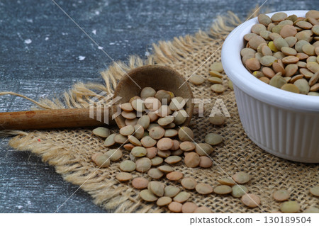 Pile lentil in wooden spoon isolated on wooden background. Top view. Pile lentil in wooden spoon isolated on wooden background. Top view. 130189504