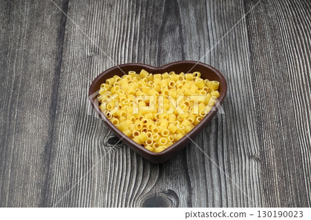 Pasta in the shape of a heart on a wooden background Pasta in the shape of a heart on a wooden background 130190023