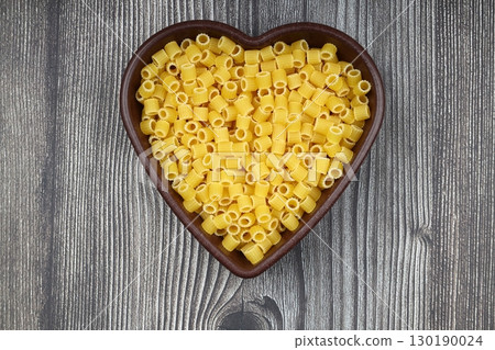 Pasta in the shape of a heart on a wooden background Pasta in the shape of a heart on a wooden background 130190024