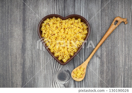 Pasta in the shape of a heart on a wooden background Pasta in the shape of a heart on a wooden background 130190026