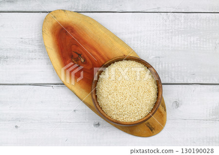 Top view closeup of freshly harvested white sesame in wooden bowl isolated on wooden background with clipping path. 130190028
