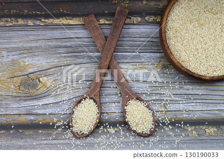 Top view closeup of freshly harvested white sesame in wooden bowl isolated on wooden background with clipping path. Top view closeup of freshly harvested white sesame in wooden bowl isolated on wooden background with clipping path. 130190033