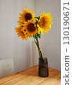 Yellow sunflowers bouquet in a glass vase on wooden table 130190671