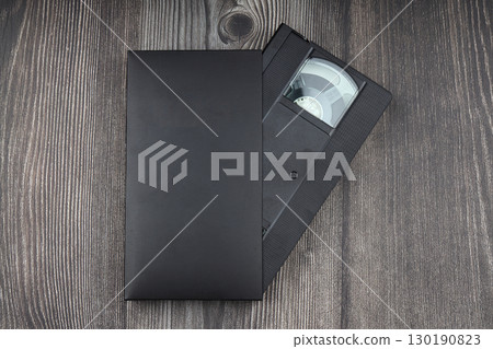 Black VHS video tape cassette with blank label isolated on wooden background 130190823
