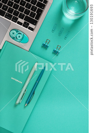 Turquoise desk with laptop, notebook and stationery. Space for your text. Study, planning, and productivity workplace. 130191693