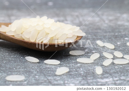White long rice close up on wooden background, uncooked raw cereals, macro. White long rice close up on wooden background, uncooked raw cereals, macro. 130192012
