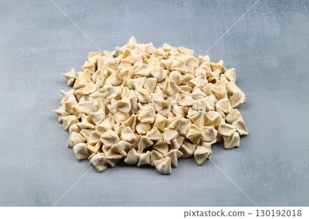 handmade manti (turkish ravioli type dumplings) on grey background, before cooking 130192018