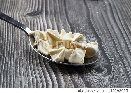 handmade manti (turkish ravioli type dumplings) on wooden spoon, before cooking. Macro handmade manti (turkish ravioli type dumplings) on wooden spoon, before cooking. Macro 130192025